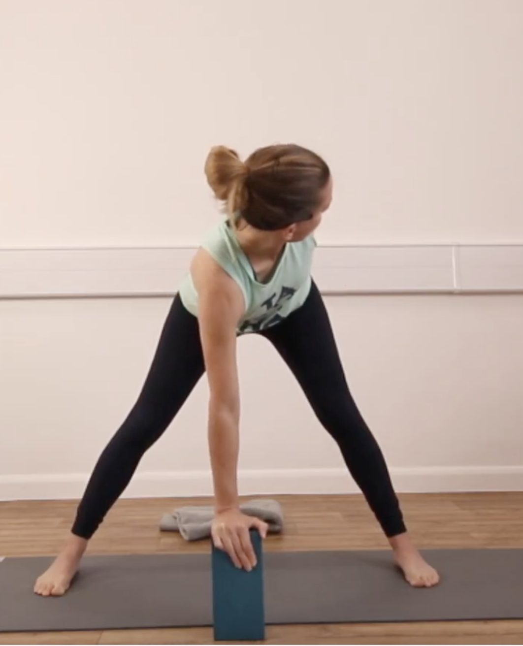 yoga teacher in twisted wide legged forward fold